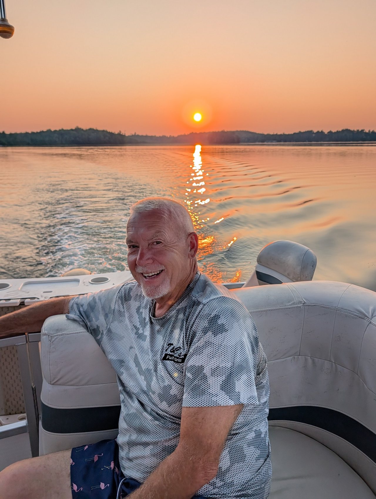 Todd smiling while riding on a boat at sunset
